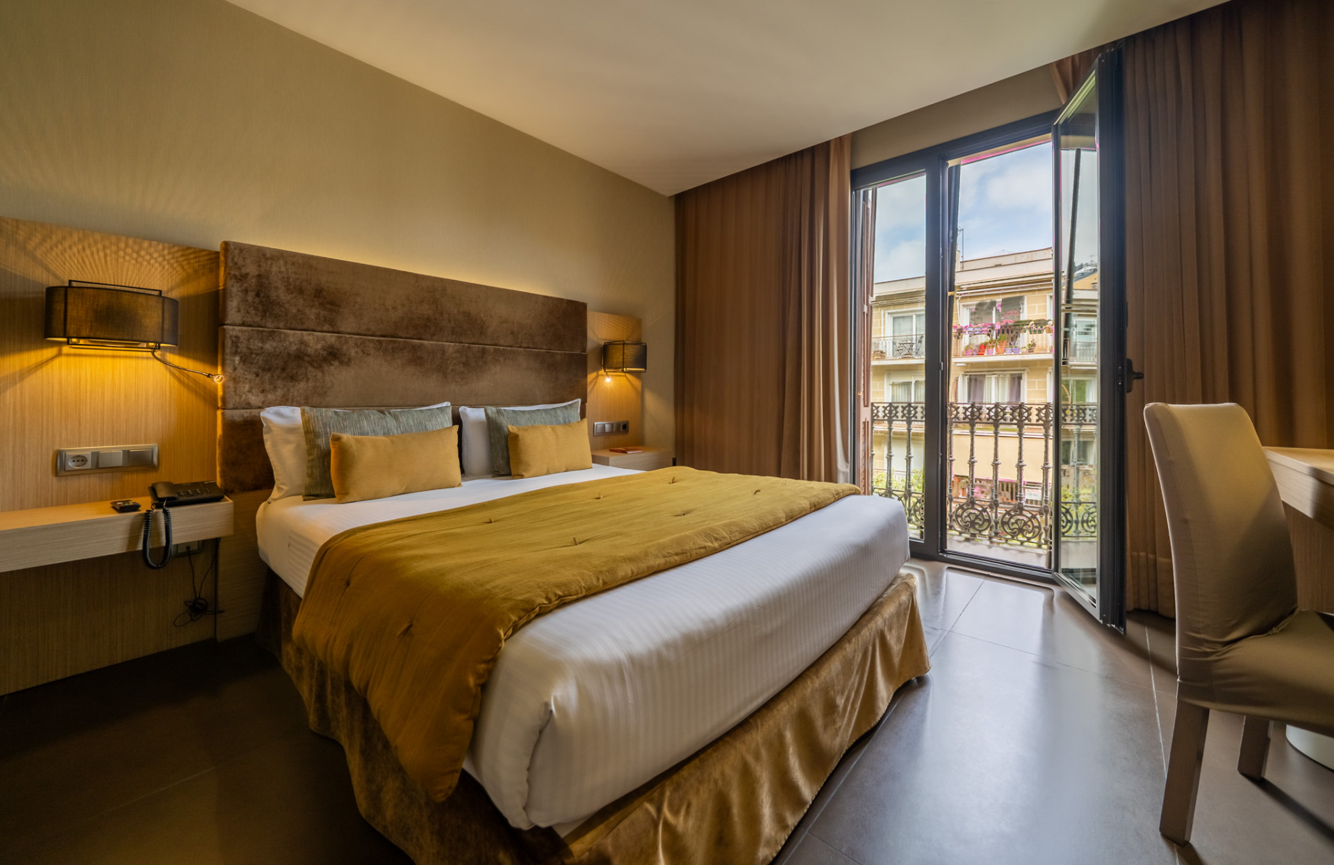 Habitación en tonos amarillos con balcón y vistas a Barcelona del hotel boutique Constanza 